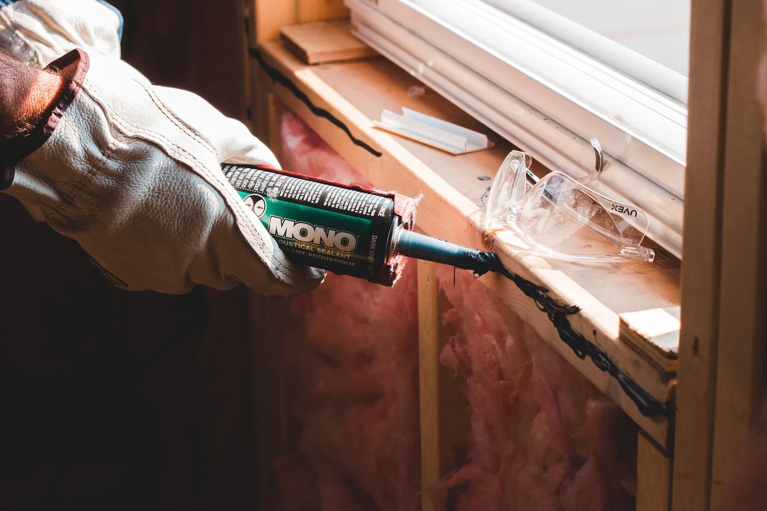 Gloved hand applying sealant to a window frame